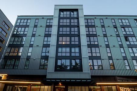 Exterior of a multi-story building featuring a glass curtain wall facade with steel framing.